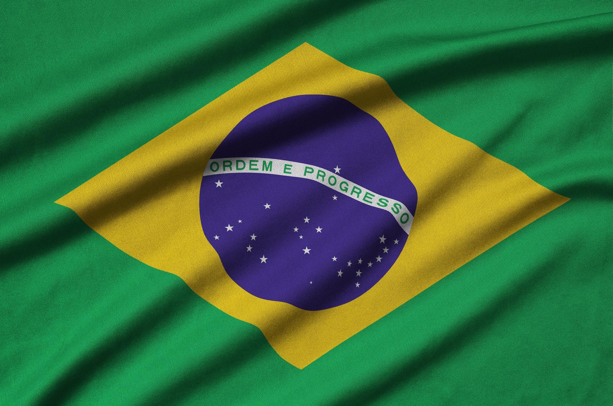 Brazil flag is depicted on a sports cloth fabric with many folds. Sport team waving banner